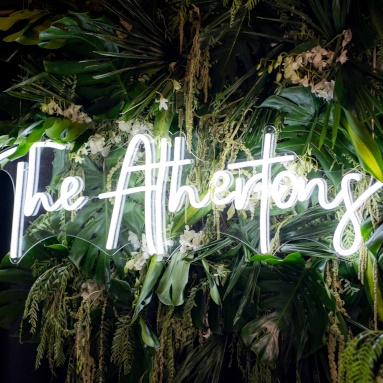 Custom Neon® white last name sign hung from a lush greenery garland