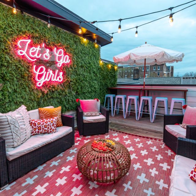 Let's Go Girls pink Custom Neon® sign on a grasswall on an outdoor deck @somerled.designs