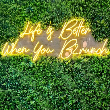 Life is better when you brunch yellow Custom Neon® sign on a grasswall @brunchharlem