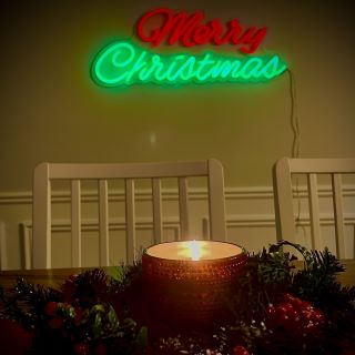 Custom Neon® red and green Merry Christmas sign above a dining room table decorated with candles and holly
