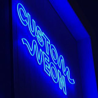 Blue Custom Neon® waterproof exterior logo sign on the Custom Neon building