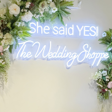Custom Neon® white bridal shop selfie station sign above the couch on a white wall @weddingshoppemi
