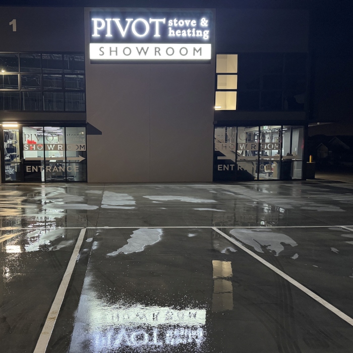 Pivot Stove & Heating front lit white LED channel letter sign shown on the building's exterior and reflected in the water at night