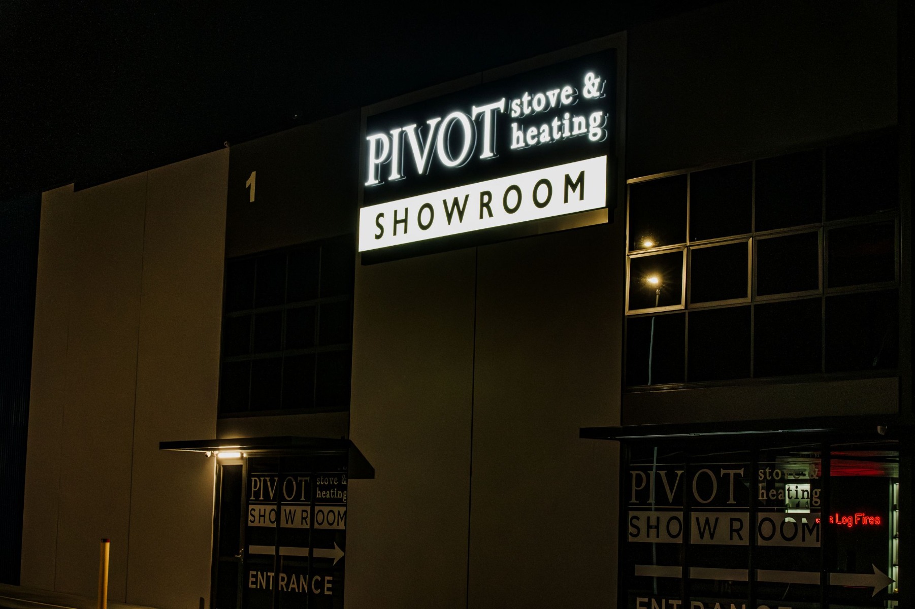 Pivot Stove & Heating front lit white LED channel letter sign made by Custom Neon®, shown on the exterior of their showroom at night