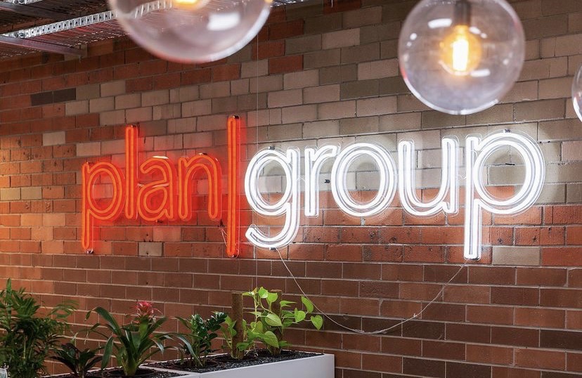 Red & white Custom Neon® logo on brick wall in office @capture_real_estate @plangroup_australia