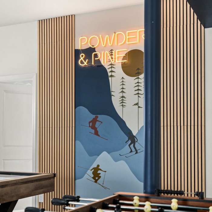 Powder and Pine orange LED Custom Neon® sign on a ski mural in the games room of an Airbnb cabin designed by Somerled