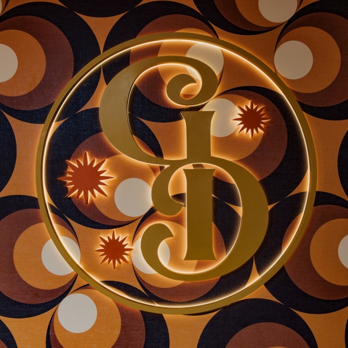 Round reverse lit logo with GD in gold coloured stainless steel and red coloured stainless steel stars made by Custom Neon®