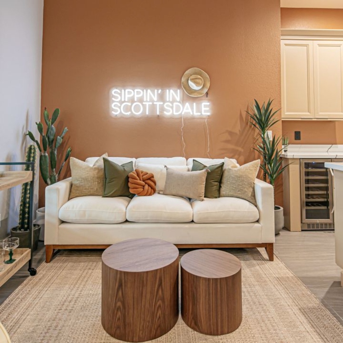 Sippin in Scottsdale white LED Custom Neon® sign on tan wall in the living room of an Airbnb designed by Somerled