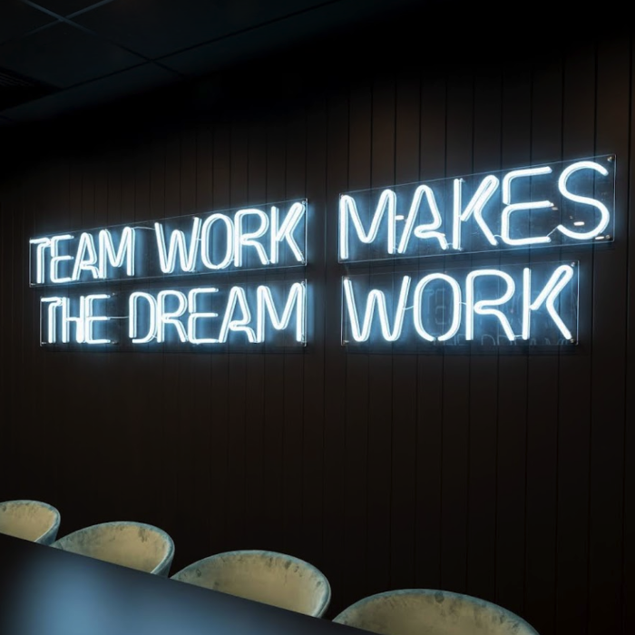 Custom Neon® white team work makes the dream work sign on dark office wall