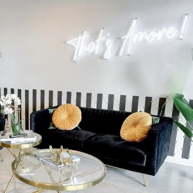 That's Amore white Custom Neon® sign on a white wall above a dark blue couch in @belairbnb