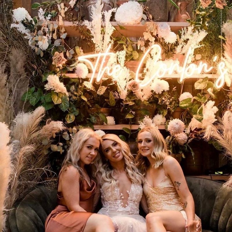 Custom Neon® wedding name sign in orange LED flex surrounded by florals