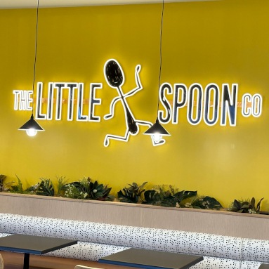 Custom Neon® black and yellow cafe logo sign on a yellow wall @thelittlespoonco