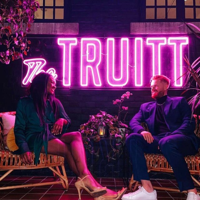 The Truitt large pink Custom Neon® sign in The Truitt hotel with guests seated in the foreground @thetruitt