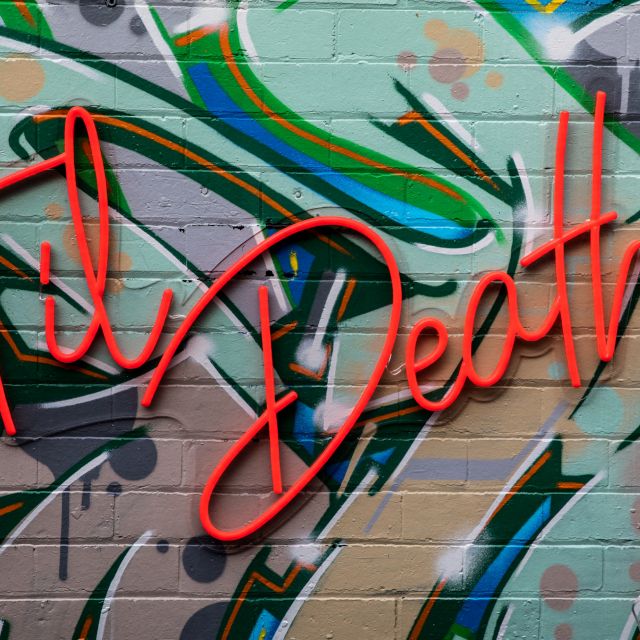 Custom Neon® red Til Death sign on a bright mural wall