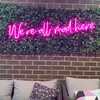 We're All Mad Here pink Custom Neon® quote sign on grasswall