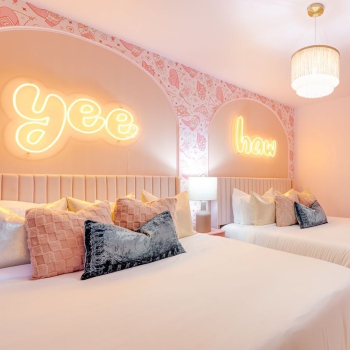 Yee Haw retro font LED Custom Neon® signs above the beds in a pink cowgirl themed double bedroom designed by Somerled