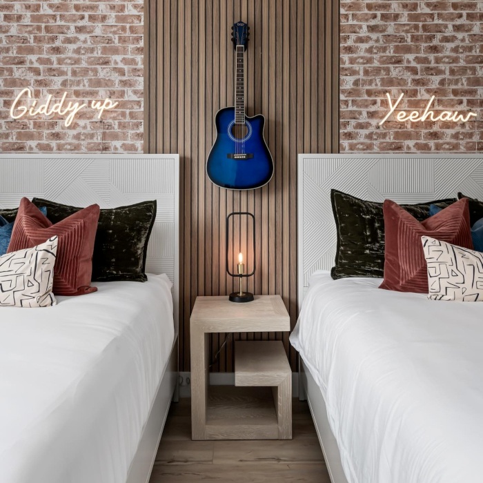 Giddy Up Yee Haw LED Custom Neon® signs on a brick wall above beds in a Western themed Airbnb designed by Somerled