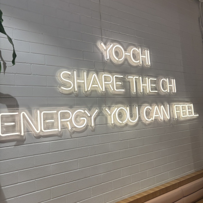 Yo-Chi tagline sign made by Custom Neon&reg; in warm white LED neon on a white brick wall @iloveyochi Victoria Park WA